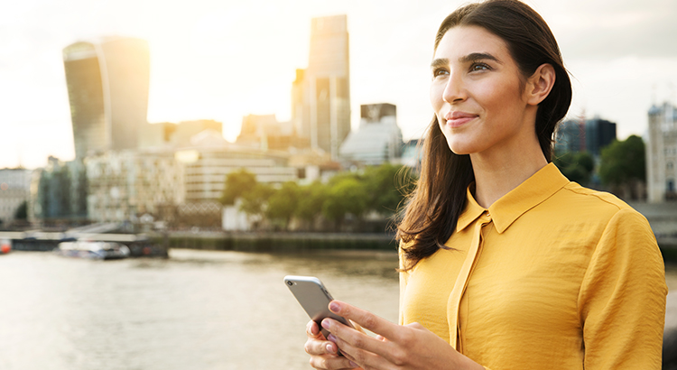 Woman looking up with mobile phone, sunset